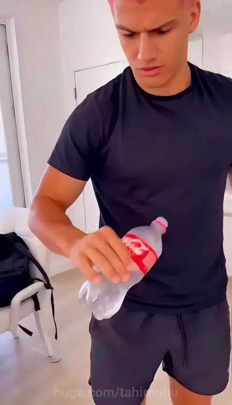 Man with pink hair performing a magic trick with a Coca-Cola bottle, making it appear to shrink and multiply.