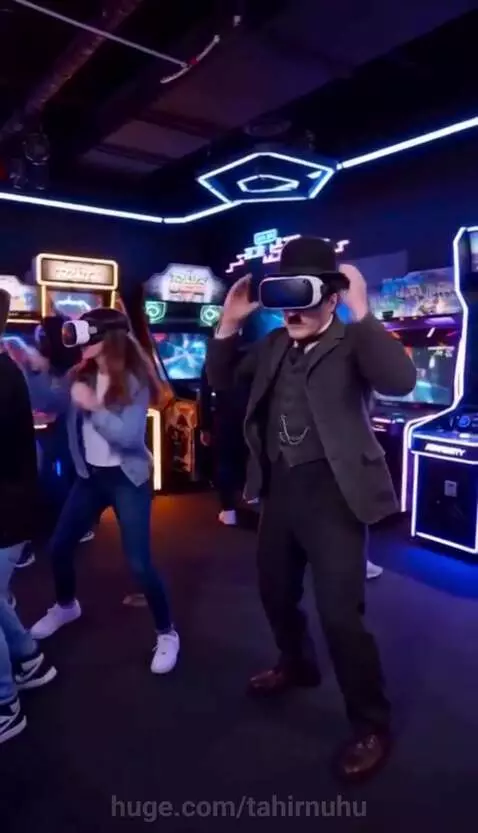 Man dressed as Charlie Chaplin in VR headset pets a small glowing white dog, after a large blue dragon appeared.