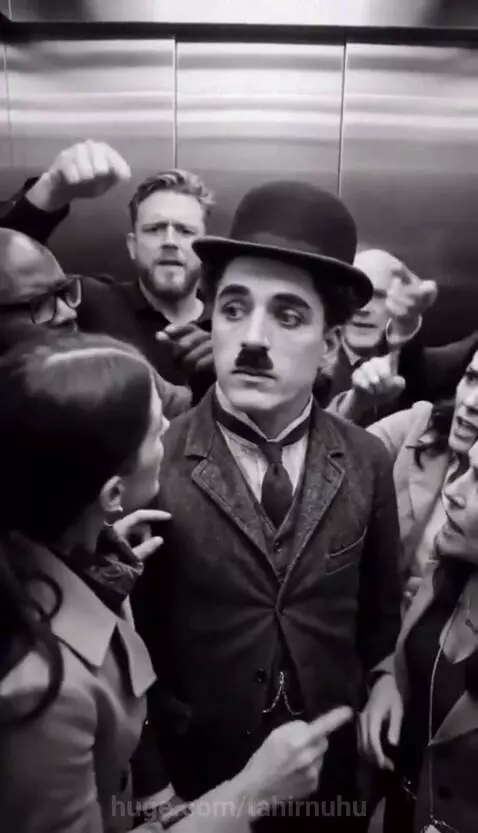 Man dressed as Charlie Chaplin sitting on a luxurious sofa in a transformed elevator, looking surprised at others.