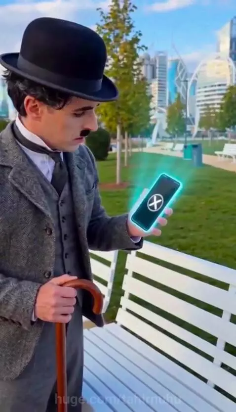 Charlie Chaplin impersonator holding a mallet, with holographic cats appearing from a smartphone.