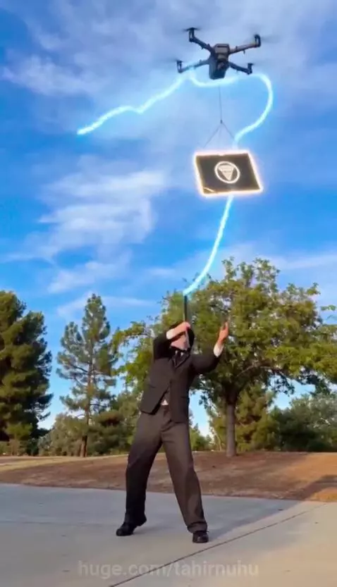 Charlie Chaplin character with a glowing cane retrieves a pizza from a drone carrying a black box.