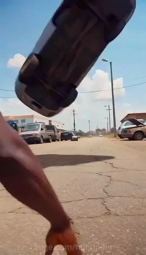 Man with magnetic powers lifting and throwing a car at a mutated man during a fight.
