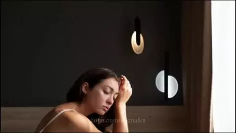 Woman looking distressed in bed at night, unable to sleep, with visual metaphors for insomnia.