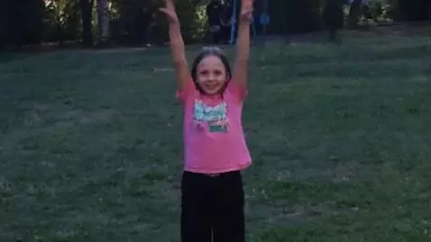 Young girl with long brown hair performing cartwheels and handstands outdoors.