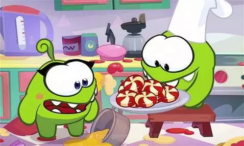 Om Nom the chef character in a chef hat presents a plate of candies in a bright kitchen.