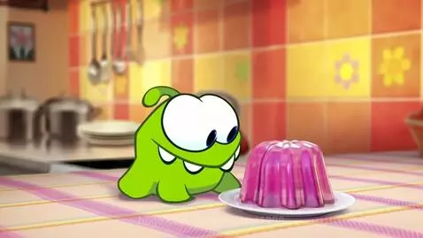 Green cartoon frog with big eyes eating a pink gelatin dessert from a white plate.