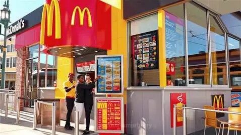 Exterior of a modern McDonald's in New Orleans with employees and a digital menu board.
