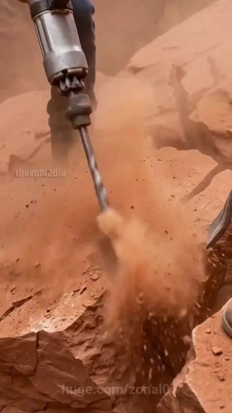 Construction workers carefully freeing a baby elephant from rocks after a rockslide.