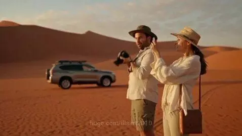 Couple surprised by a Carnotaurus dinosaur chasing a bull across desert sand dunes.