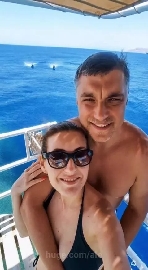 Couple enjoying a romantic dinner on a yacht at sunset with a lavish table spread.