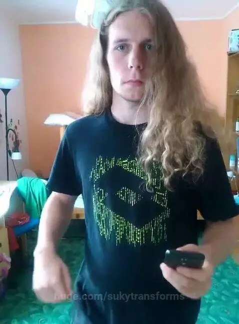 Person with long blonde hair in a pink dress, makeup applied, smiling after a transformation.