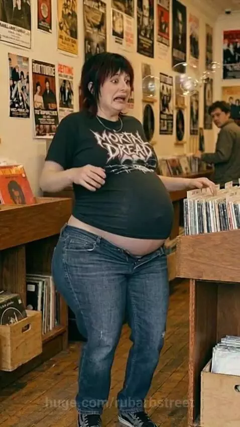 Pregnant woman in a record store with exposed belly, blowing bubbles and reacting with panic to rapid body expansion.