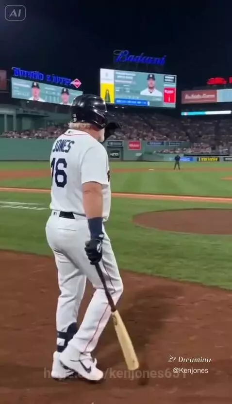 Boston Red Sox player Ken Jones in uniform at night, swinging a baseball bat and hitting a home run.