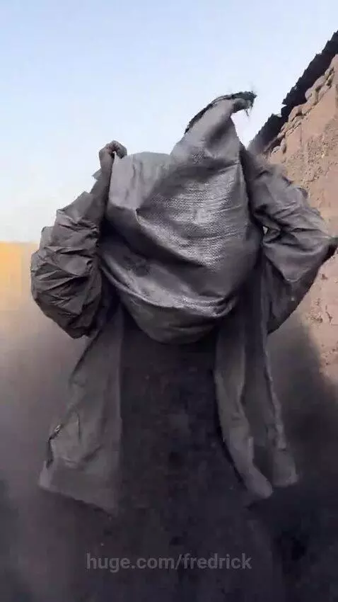 Person covered head-to-toe in dark dust after a large dust cloud explodes from a bag.