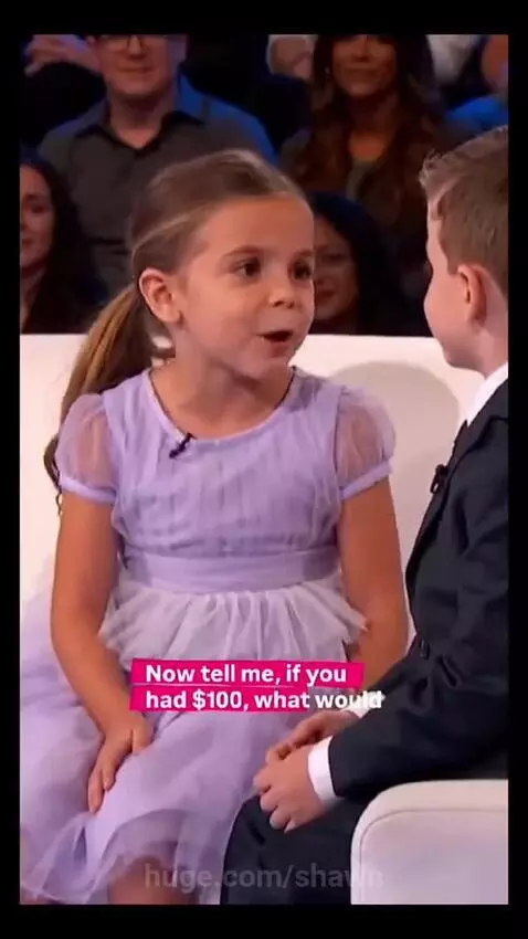 Young boy in a suit and girl in a dress on a couch, discussing love and money.