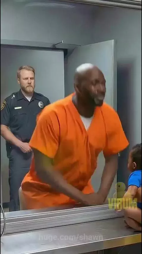 Inmate in orange jumpsuit holding two babies, with mother and police officer smiling in the background.