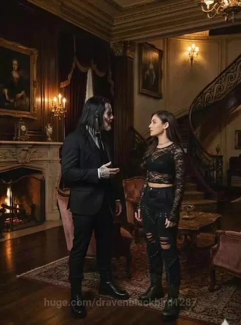 Man and woman in dramatic gothic attire in a grand, dimly lit room with a fireplace and staircase.