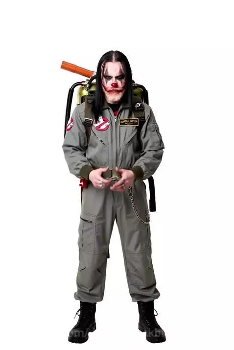 Person in Ghostbusters uniform with clown makeup holding a proton pack and aiming it forward.