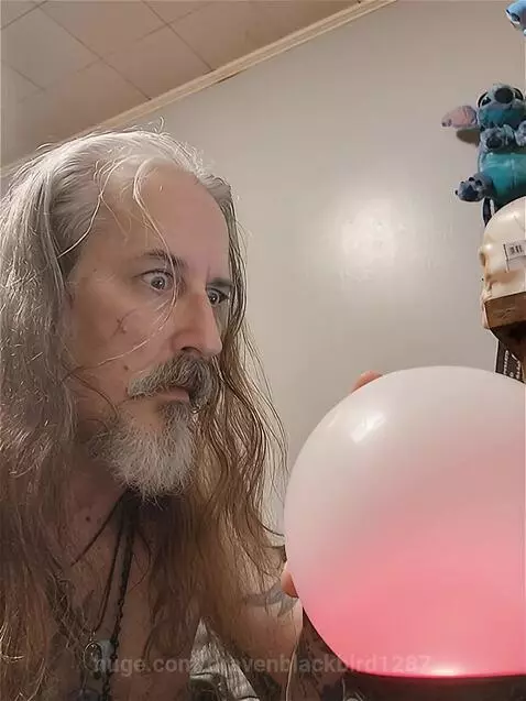 Man with long gray hair and beard startled by a fiery explosion from a glowing red sphere.