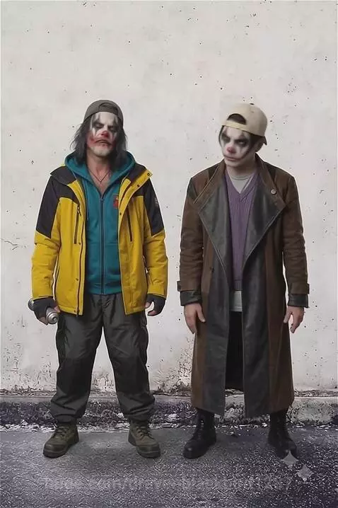 Two men in clown makeup and street-style clothing stand against a wall, one holding a spray can, the other making a rock gesture.