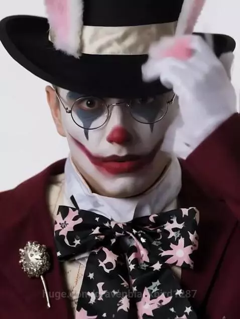 Person in a theatrical costume with bunny ears, top hat, clown makeup, and a pocket watch.