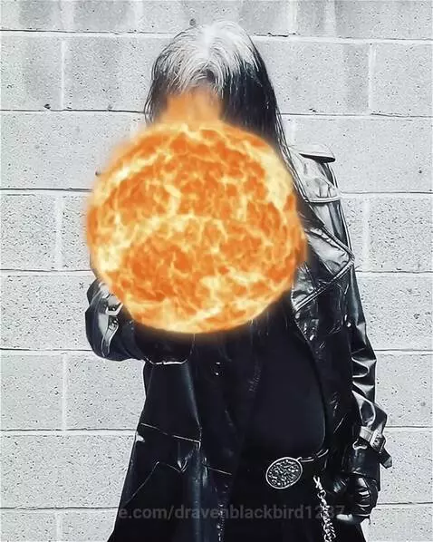 Person with dark and white hair in a black trench coat conjures a glowing orange fire orb with their right hand.