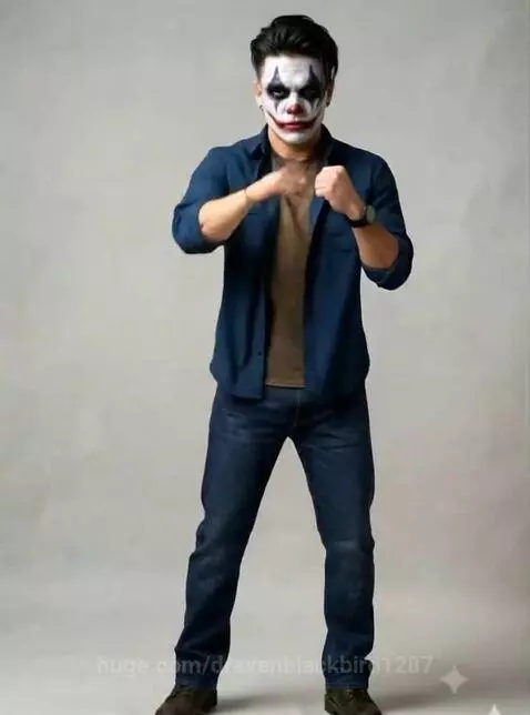 Man with white, black, and red clown face paint in a boxing stance against a plain background.