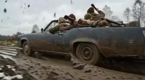 Group of adults covered in mud smiling and laughing after driving a vintage convertible through a muddy rural road.