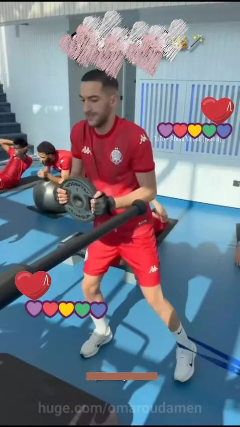 Athletes in red sportswear training in a modern gym with city views, including Ziyech.