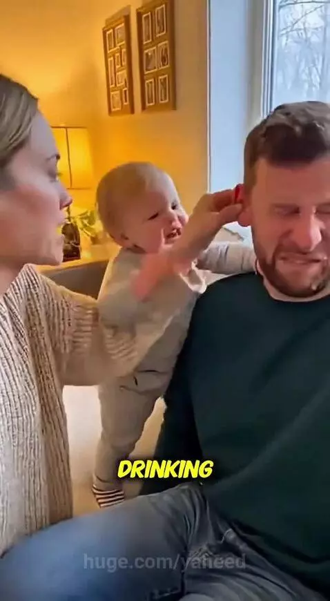 Baby grabs dad's ear while mom playfully scolds him, creating a funny family moment.