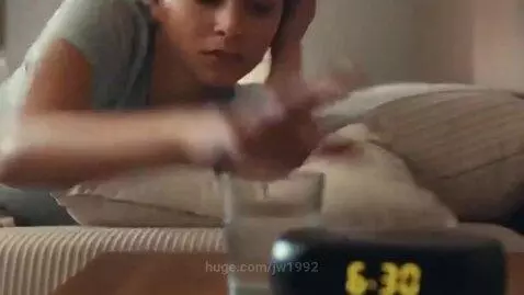 Young woman startled awake by alarm clock, then gasps at a giant man's face peering through window blinds.