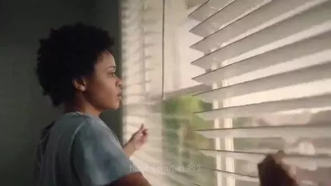 A woman startled as a giant woman's mouth fills her bedroom window.
