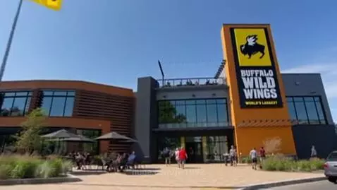 Exterior of the world's largest Buffalo Wild Wings restaurant with a large sign and outdoor seating.