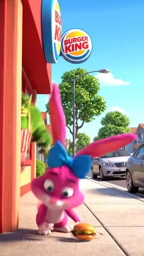 Pink cartoon rabbit with a burger peeking from behind a Burger King, facing a stern green monster.