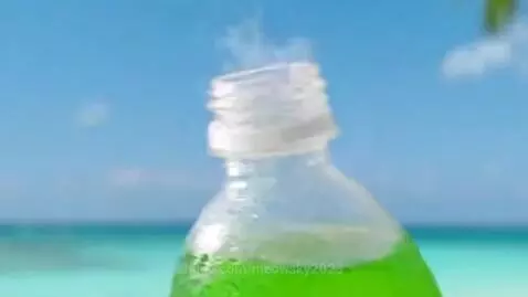 Hawaiian Punch Summer Green Aqua Fresh Mint bottle splashing in water with mint leaves on a sunny beach.