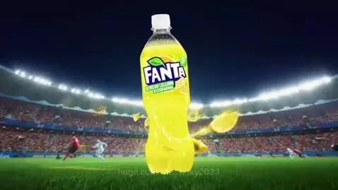 Fanta Yellow Lemon Extra Sour bottle in a football stadium with lemon slices and liquid splashes.