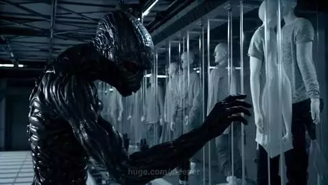 Alien creature with glowing red eyes and textured body observes humans in futuristic glass containers.