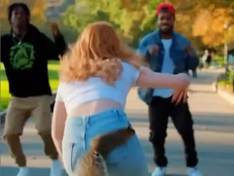 Woman in white crop top and jeans with a squirrel on her hip, dancing energetically.