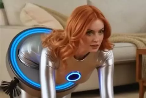 Woman in a silver suit with a glowing blue chest piece, crawling on the floor like a robot vacuum.