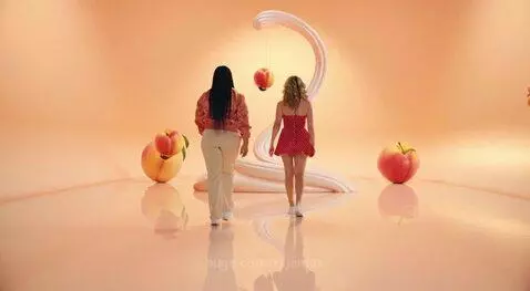 Two women dancing in a peach and cream themed setting with large peaches and swirling cream elements.