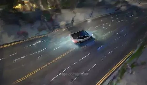 Aerial view of a modern city street at night with cars driving and city lights illuminating the scene.