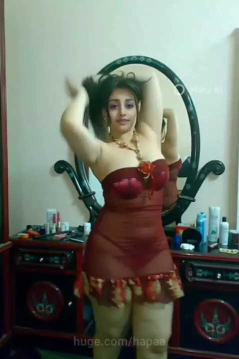 Woman with dark hair in a strapless red dress posing by a mirror, revealing red underwear.