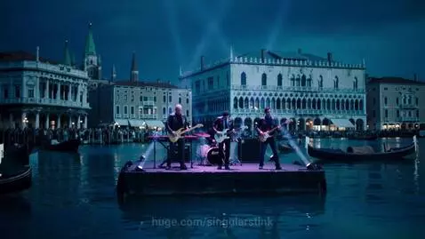 Pink Floyd performing on a floating stage in a Venice canal at night, illuminated by spotlights.