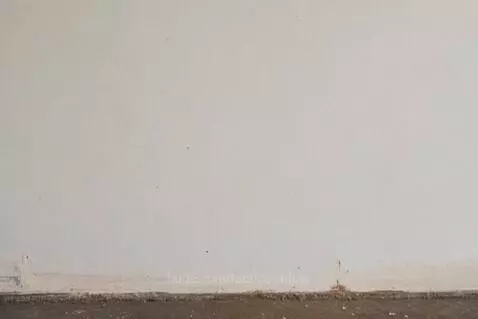 A roll of toilet paper mid-air after being thrown at a plain wall, about to fall.