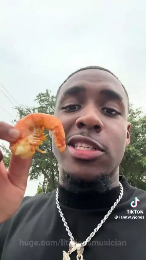 Young man humorously reviewing a seafood boil outside an Autozone store.
