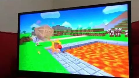 Mario plush toy sitting on a red couch, holding a controller and looking frustrated.