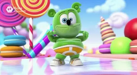 Green Gummy Bear character dancing in a colorful candy landscape with lollipops and cupcakes.