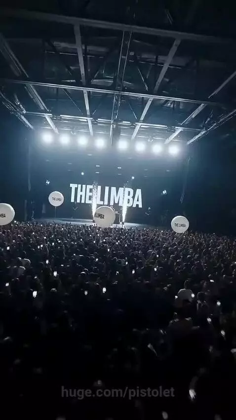 The Limba performing on a stage with pyrotechnics, wearing a fur coat and cap.