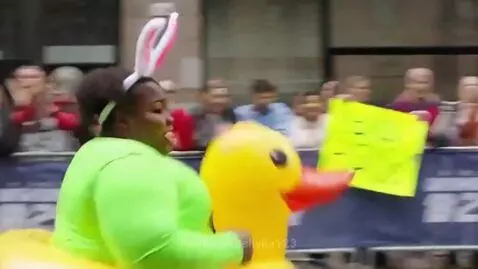 Runner in a vibrant, humorous costume with a neon green suit, pink tutu, rainbow socks, bunny ears, and a yellow inflatable duck, running a marathon.