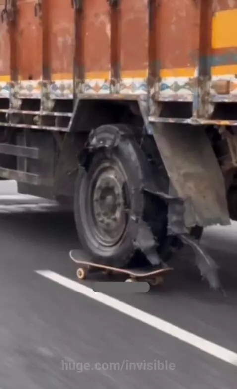 Close-up of a truck's damaged rear tire dragging a skateboard, with sparks flying from the friction.